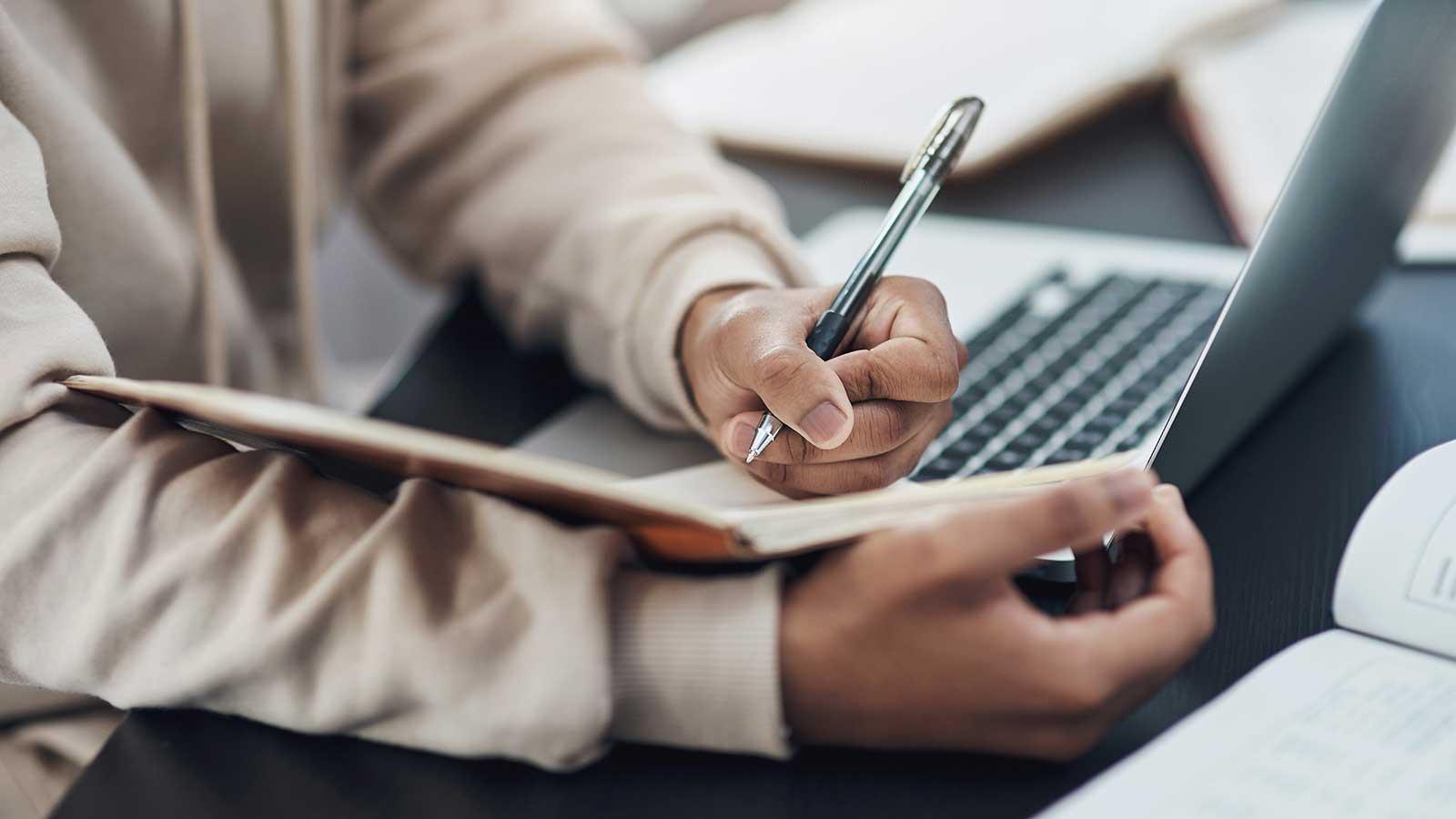 Person taking notes from laptop representing 商业研究 program at Clarkson